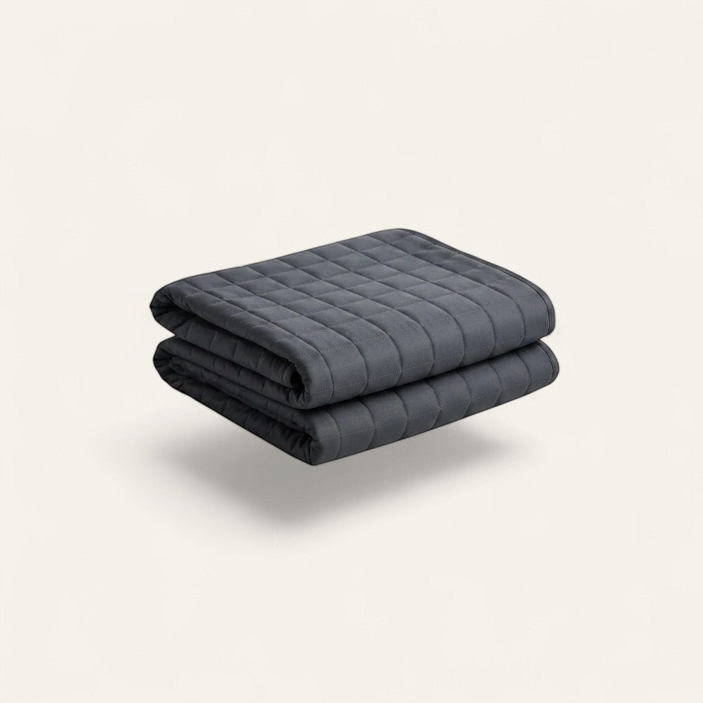 Driftward charcoal grey cotton weighted blanket with quilted stitching, folded.